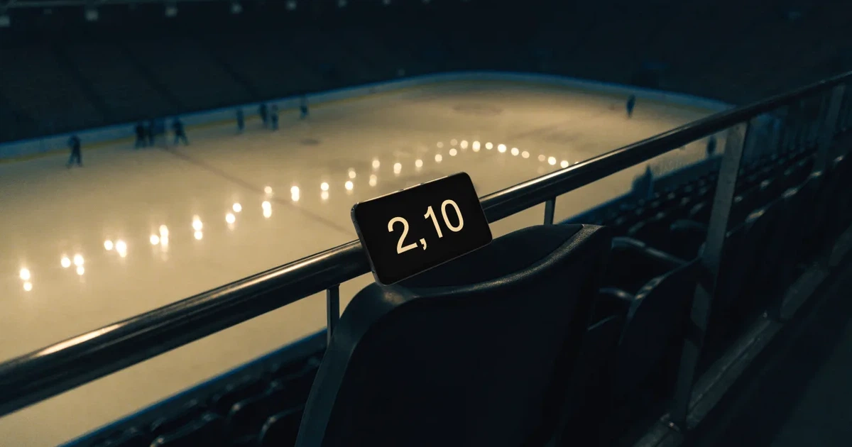 Eine Eishockeyhalle von der Tribüne aus gesehen, spiegelglatte Eisfläche, Banden ohne Schriftzüge, helles Flutlicht.