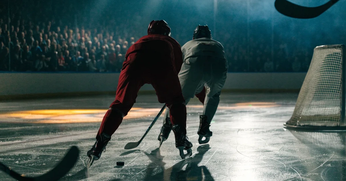 Eine leere Eisfläche in einer Halle mit Banden und Flutlicht, auf dem Eis liegt ein einzelner Puck.